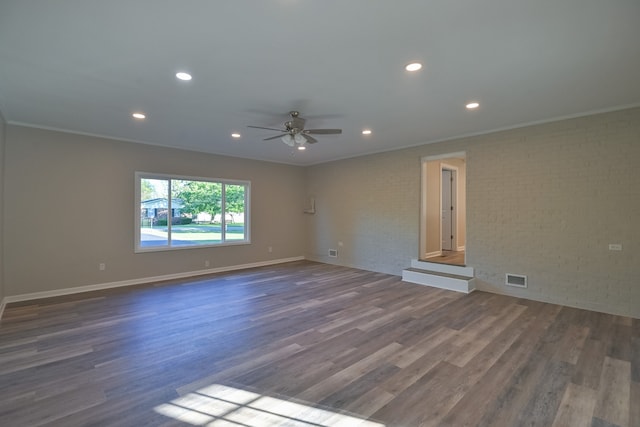 unfurnished room featuring ceiling fan, brick wall, dark hardwood / wood-style floors, and ornamental molding