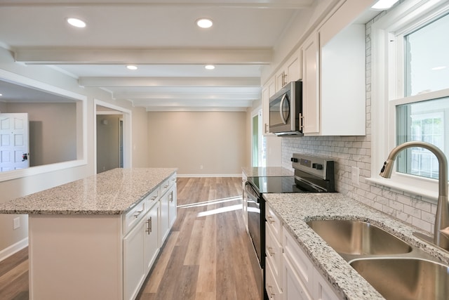 kitchen with light stone countertops, white cabinets, stainless steel appliances, sink, and beam ceiling