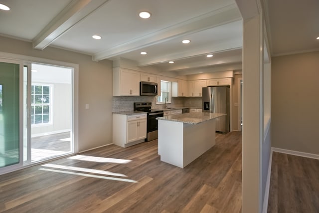 kitchen featuring appliances with stainless steel finishes, white cabinetry, a kitchen island, and beamed ceiling