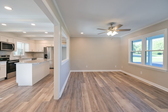 kitchen with stainless steel appliances, a center island, white cabinetry, and sink