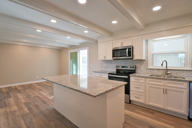 kitchen with white cabinets, a center island, stainless steel appliances, beamed ceiling, and sink