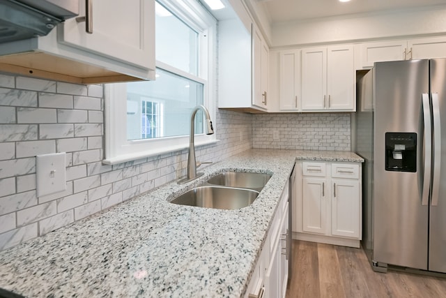 kitchen featuring tasteful backsplash, sink, light stone countertops, stainless steel fridge with ice dispenser, and white cabinets