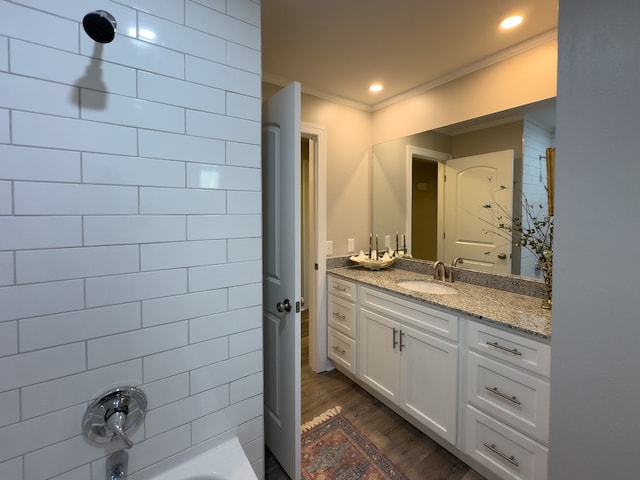 bathroom featuring ornamental molding, tiled shower / bath combo, hardwood / wood-style floors, and vanity