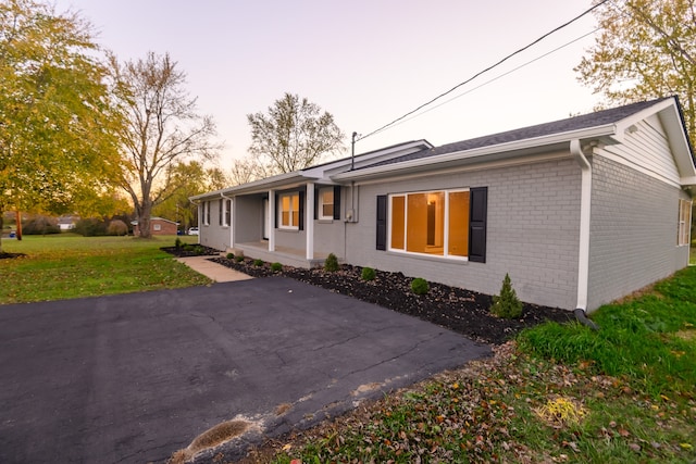 property exterior at dusk with a yard and a patio