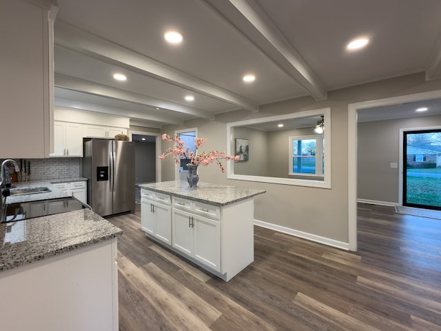 kitchen featuring stainless steel refrigerator with ice dispenser, beamed ceiling, white cabinets, and a center island