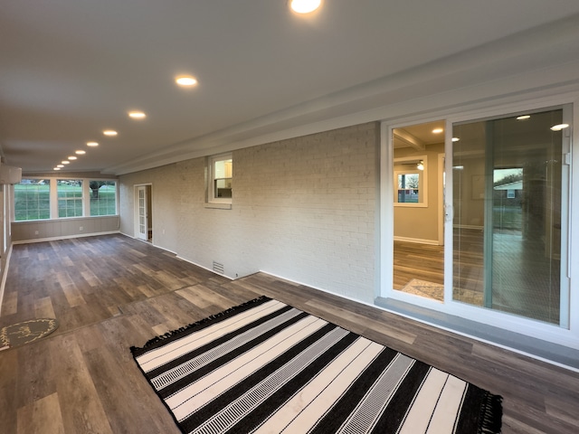 interior space featuring dark wood-type flooring and brick wall