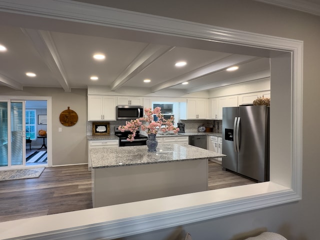 kitchen with light stone countertops, white cabinets, stainless steel appliances, beamed ceiling, and backsplash