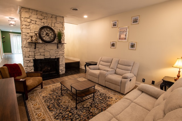 living room with wood-type flooring and a stone fireplace