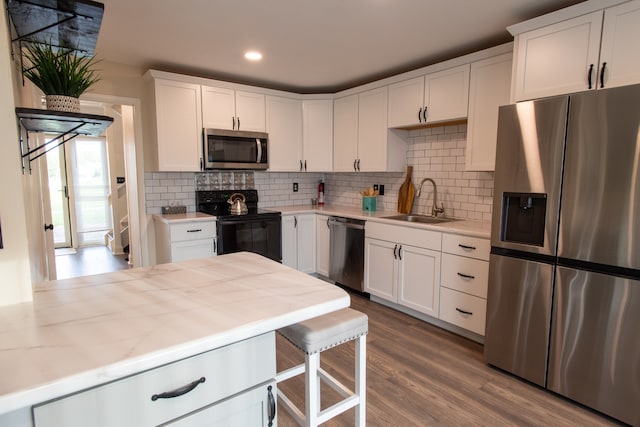 kitchen with white cabinets, hardwood / wood-style flooring, appliances with stainless steel finishes, and sink