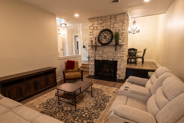 living room with wood-type flooring and a stone fireplace