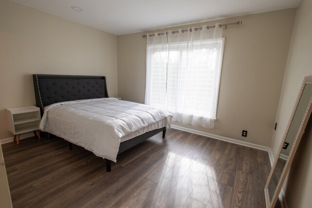 bedroom with multiple windows and dark wood-type flooring