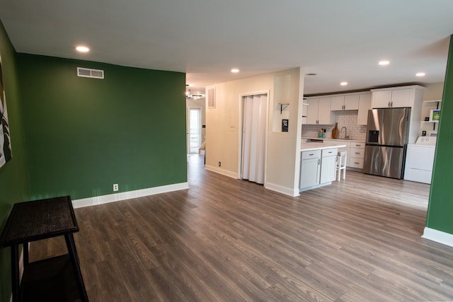 kitchen featuring wood-type flooring, washer / dryer, tasteful backsplash, stainless steel refrigerator with ice dispenser, and white cabinetry