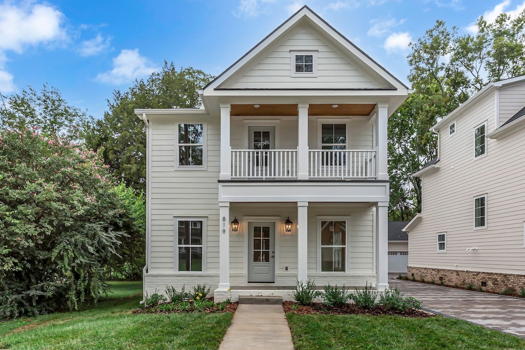 view of front of house with a balcony, a porch, and a front yard