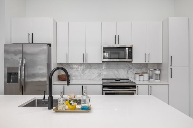 kitchen with stainless steel appliances, decorative backsplash, and white cabinetry