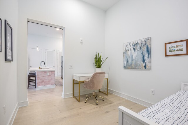 home office with light wood-type flooring and sink