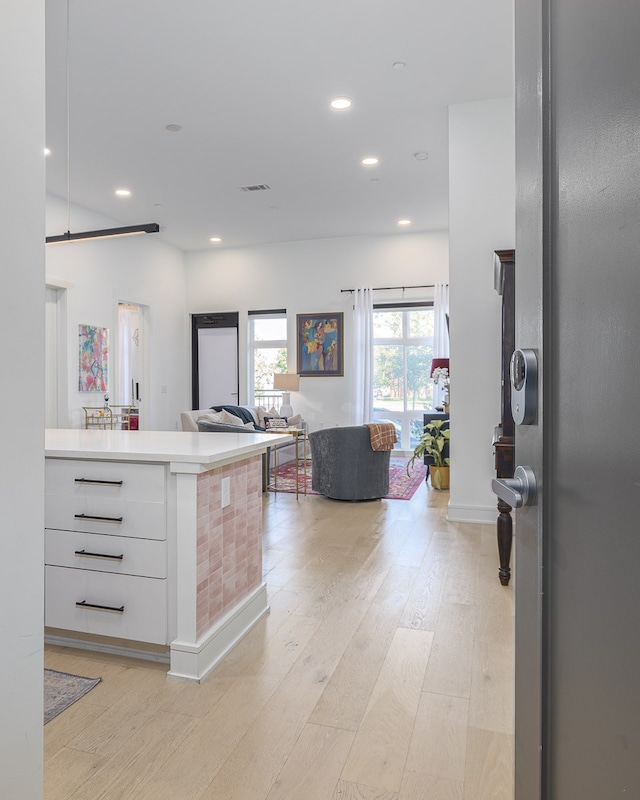 kitchen featuring kitchen peninsula, light wood-type flooring, and white cabinetry