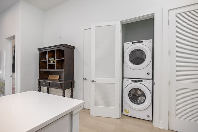 washroom with light wood-type flooring and stacked washer / drying machine