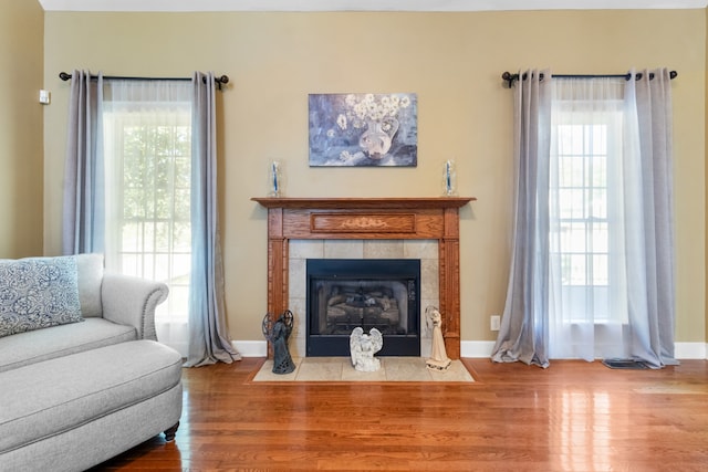 sitting room with a tiled fireplace, plenty of natural light, and hardwood / wood-style floors