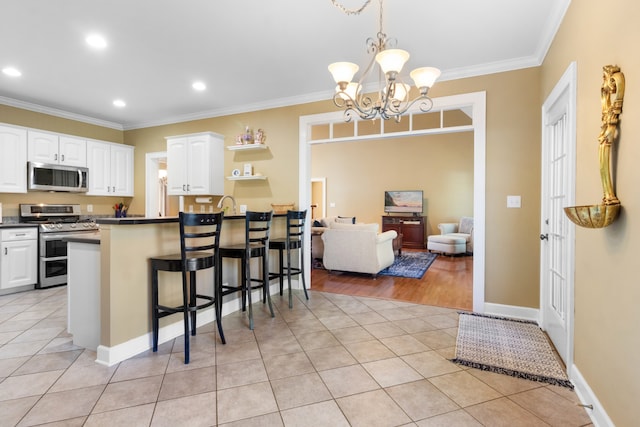 kitchen with stainless steel appliances, light tile patterned flooring, hanging light fixtures, white cabinetry, and a kitchen bar