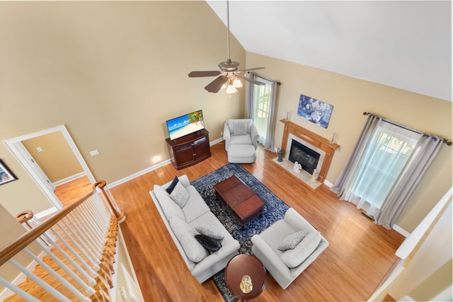 living room with high vaulted ceiling, a wealth of natural light, a high end fireplace, and wood-type flooring