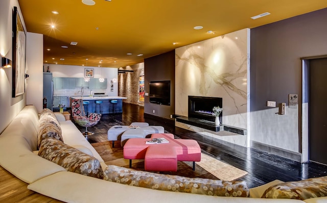 living room featuring sink, a premium fireplace, and hardwood / wood-style floors