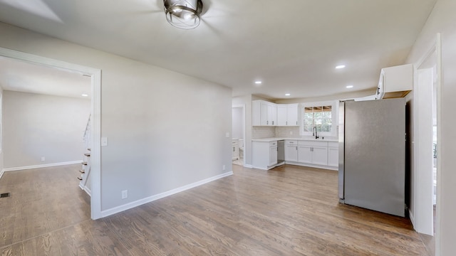 kitchen with white cabinets, appliances with stainless steel finishes, light hardwood / wood-style flooring, and sink