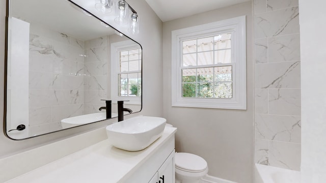 full bathroom with tiled shower / bath, vanity, toilet, and a wealth of natural light