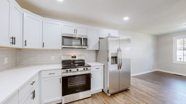 kitchen with white cabinetry, stainless steel appliances, and light hardwood / wood-style flooring