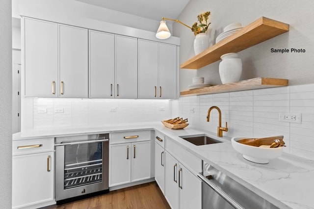 kitchen featuring beverage cooler, light hardwood / wood-style flooring, sink, and white cabinets