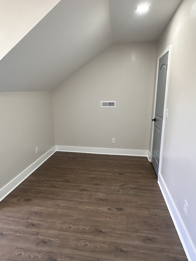 additional living space with vaulted ceiling and dark wood-type flooring