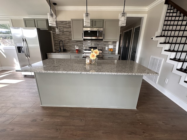 kitchen featuring light stone countertops, dark wood-type flooring, hanging light fixtures, appliances with stainless steel finishes, and gray cabinets