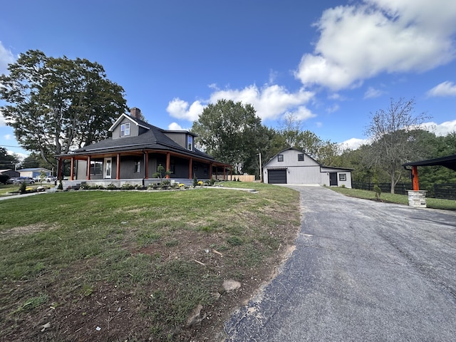 country-style home with a front lawn, a porch, an outdoor structure, and a garage