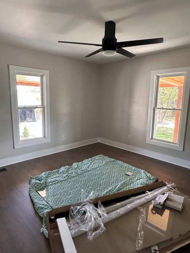 empty room featuring ceiling fan, dark hardwood / wood-style flooring, and a wealth of natural light