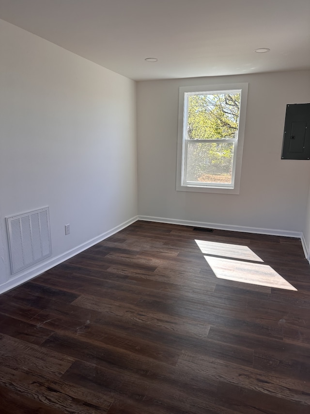 spare room featuring electric panel and dark hardwood / wood-style flooring