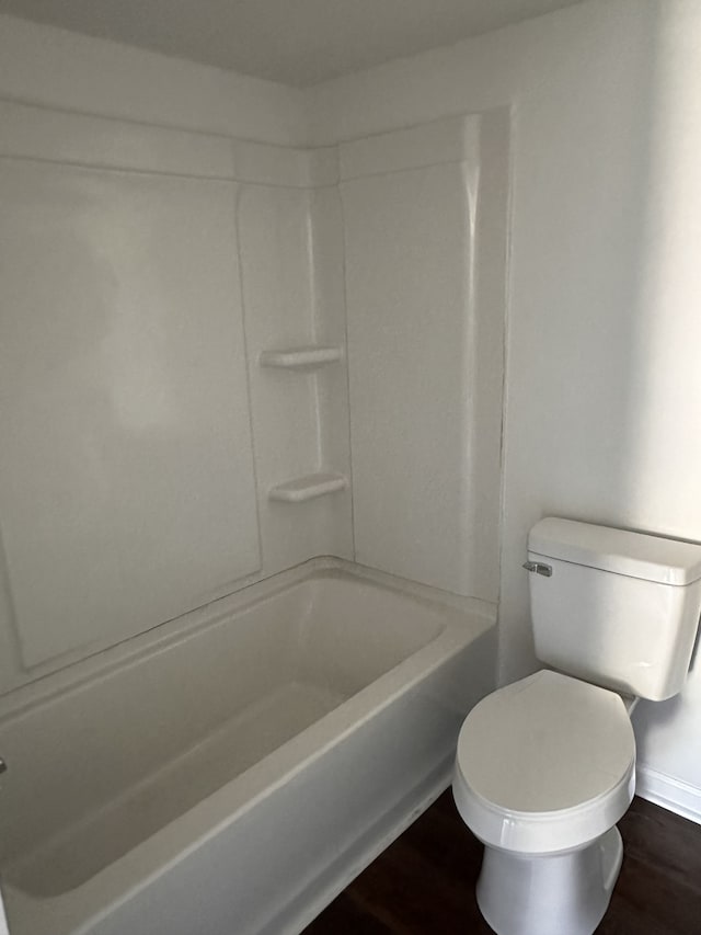 bathroom with hardwood / wood-style floors, toilet, and shower / washtub combination