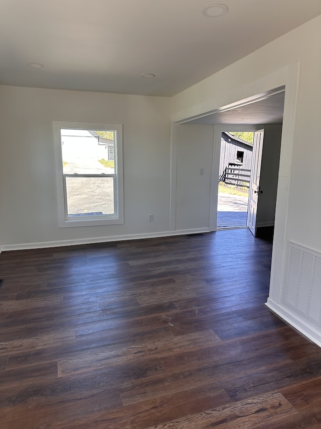 empty room with a wealth of natural light and dark wood-type flooring