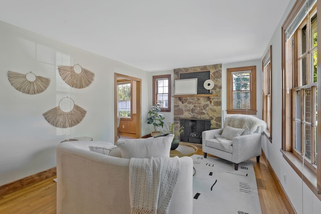 living room with light hardwood / wood-style floors, a fireplace, and a healthy amount of sunlight