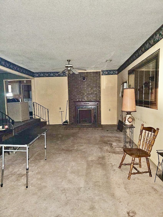 carpeted living room with ceiling fan, a textured ceiling, and a fireplace