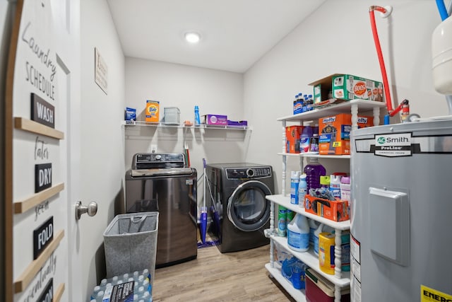 washroom featuring electric water heater, light hardwood / wood-style floors, and washer and dryer