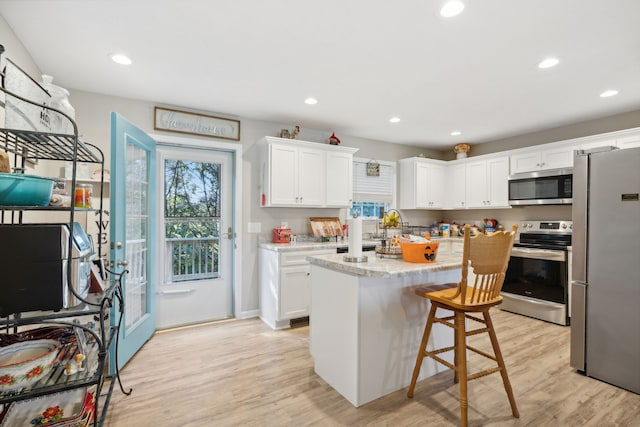 kitchen with white cabinetry, light hardwood / wood-style floors, appliances with stainless steel finishes, and a kitchen island