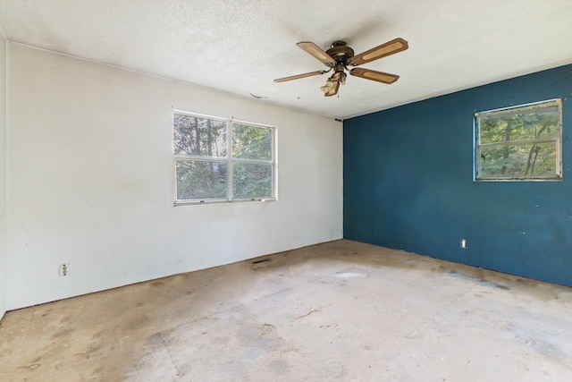 spare room featuring ceiling fan, a textured ceiling, and concrete flooring