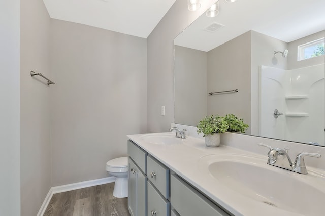 bathroom featuring wood-type flooring, a shower, vanity, and toilet