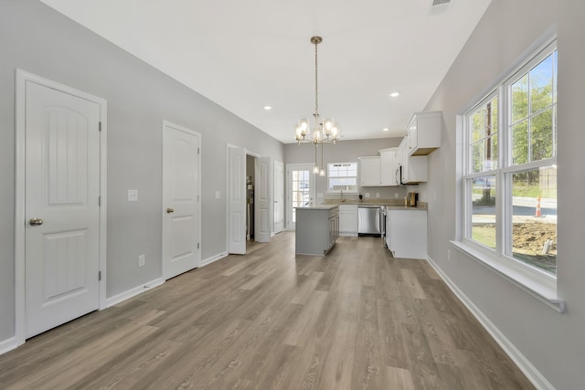 kitchen featuring stainless steel dishwasher, decorative light fixtures, white cabinetry, a center island, and light wood-type flooring