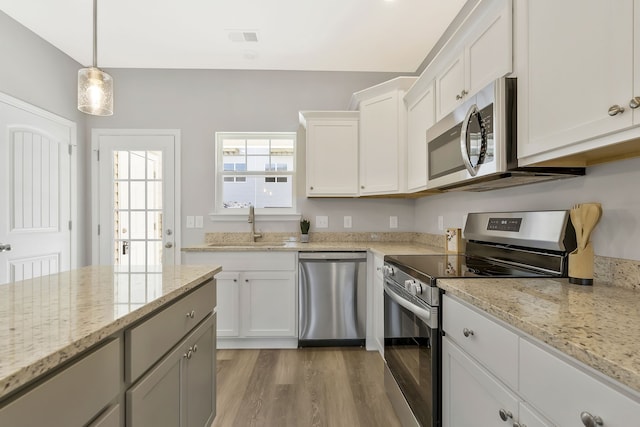 kitchen with light stone counters, sink, white cabinetry, appliances with stainless steel finishes, and light hardwood / wood-style floors