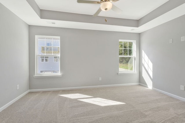 empty room with ceiling fan, light colored carpet, and plenty of natural light