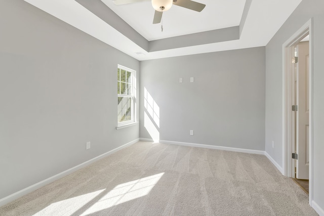 carpeted empty room with a tray ceiling and ceiling fan