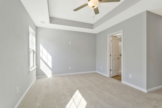 carpeted spare room featuring a raised ceiling and ceiling fan