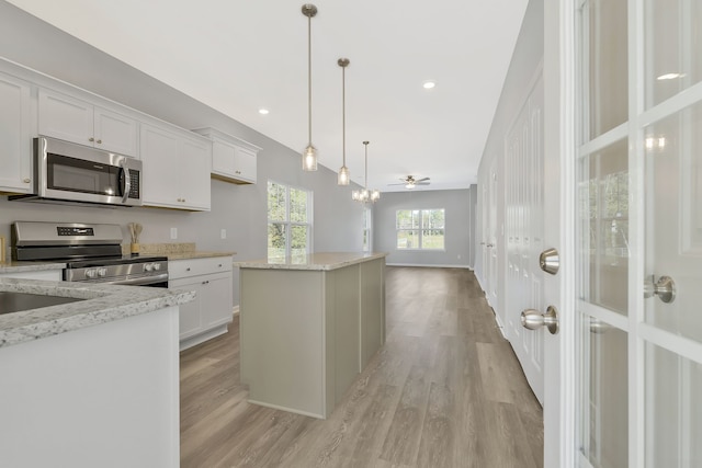 kitchen with pendant lighting, stainless steel appliances, white cabinetry, and a center island