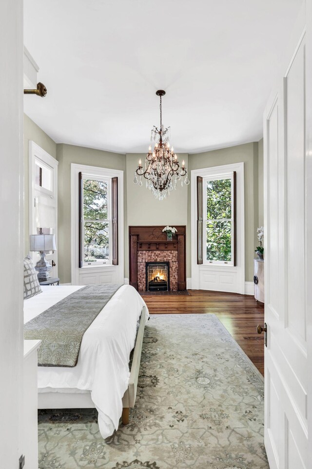 bedroom featuring multiple windows, dark wood-type flooring, and an inviting chandelier