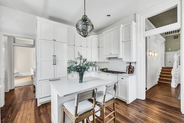 kitchen with stainless steel gas stovetop, pendant lighting, dark hardwood / wood-style flooring, and white cabinetry